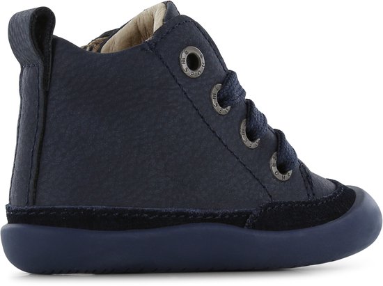 Zijkant van een donkerblauwe leren bootie met veters en suède accenten. Heeft een trekker aan de achterkant.