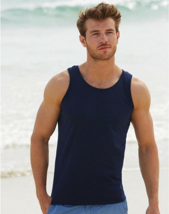 Le mannequin porte un débardeur bleu marine sur une plage avec des vagues en arrière-plan.
