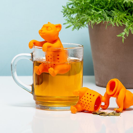 Oranje katvormige theefilter in een mok met thee, naast twee andere katvormige theefilters.