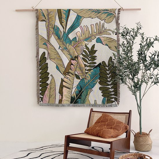 Beige deken met botanische print van bladeren, hangend aan een muur.