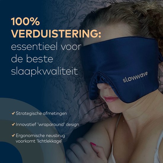 Een vrouw met krullend haar draagt een donkerblauw zijden slaapmasker. Tekst: '100% VERDUISTERING: essentieel voor de beste slaapkwaliteit'.