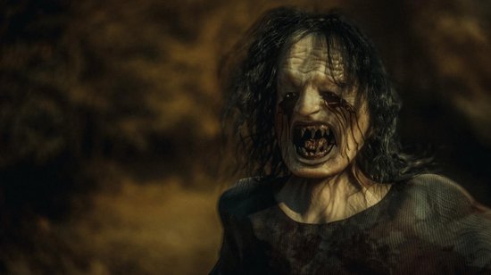 Een monsterlijke figuur met bloed uit de ogen en scherpe tanden, met lang, rommelig haar.