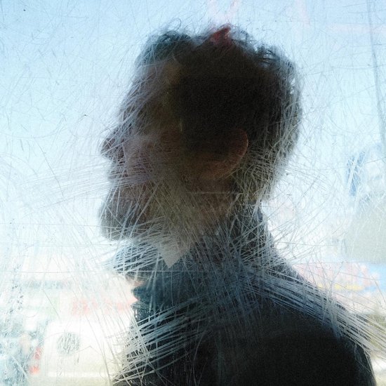 Profil d'un homme aux cheveux ébouriffés, vu à travers une fenêtre rayée. Bleu clair avec un arrière-plan flou.