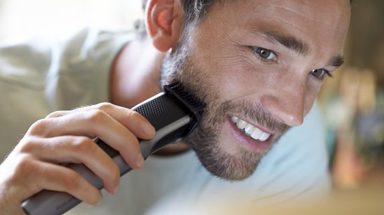 Man trimt zijn baard met een zilveren Philips baardtrimmer.
