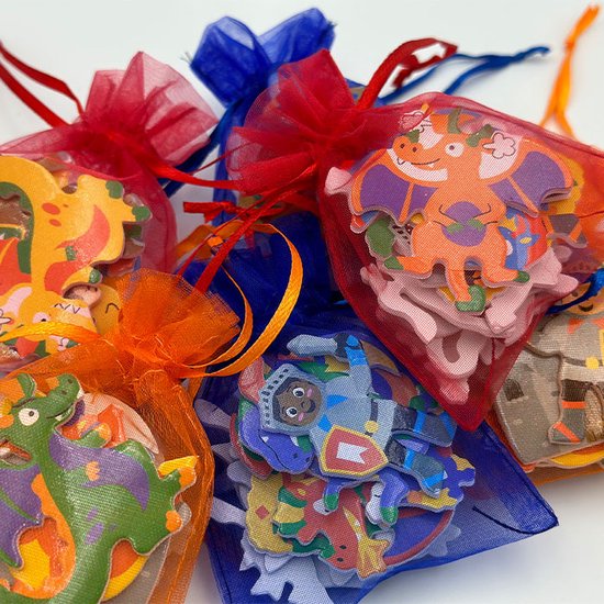 Verschillende uitdeelzakjes gevuld met foamstickers van draken en ridders in kleuren zoals oranje, groen, paars, blauw en rood.