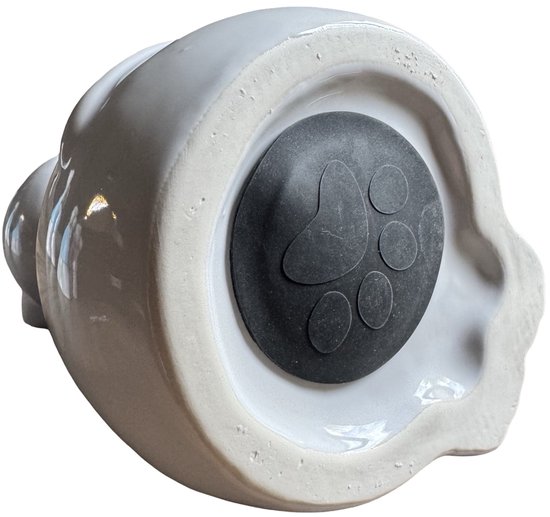 Onderkant van een witte keramische kattenurn met een zwarte dop met pootafdruk.