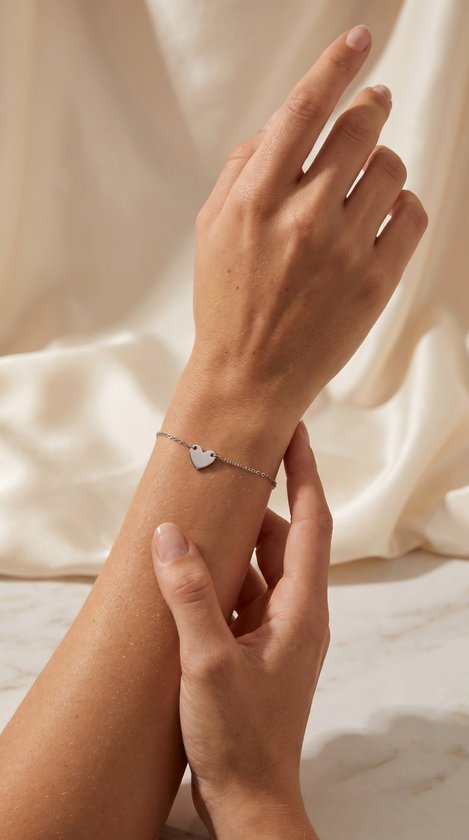 Damesarm met zilverkleurige schakelarmband met hartje.