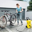 Vrouw spuit met hogedrukreiniger een fiets schoon.