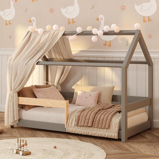 Grijs huisjesbed met bedhemel, lakentjes en decoratieve kussens.
