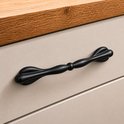 Zwarte meubelgreep op een lichte, beige lade met houten bovenblad.