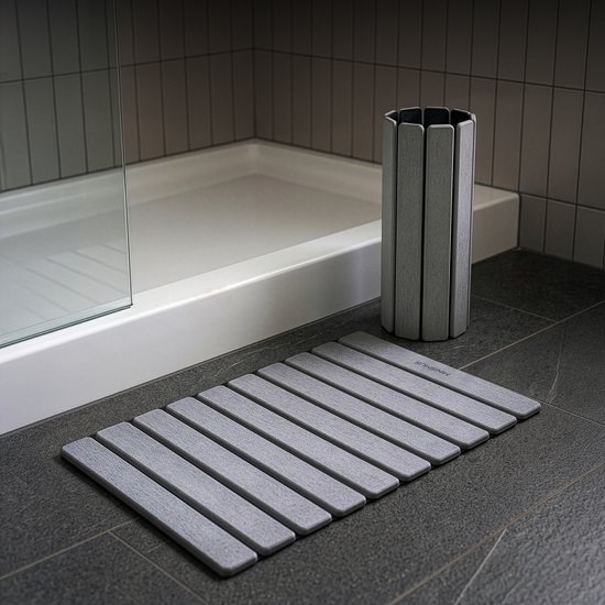 Grijze ribbelmat en grijze prullenbak naast een douche.