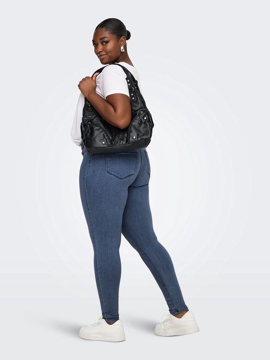 Model draagt een blauwe skinny jeans met een witte t-shirt en zwarte schoudertas.