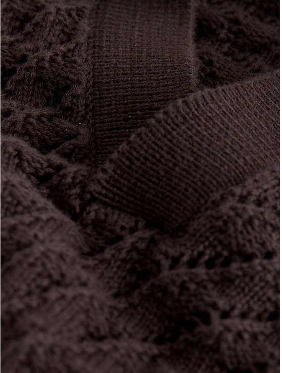 Detail van een bruin gebreid poloshirt met visgraatpatroon.