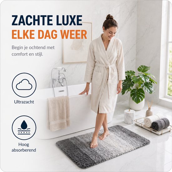 Een vrouw in een beige badjas stapt op een grijze, ombre badmat bij een badkuip. Zacht, absorberend.