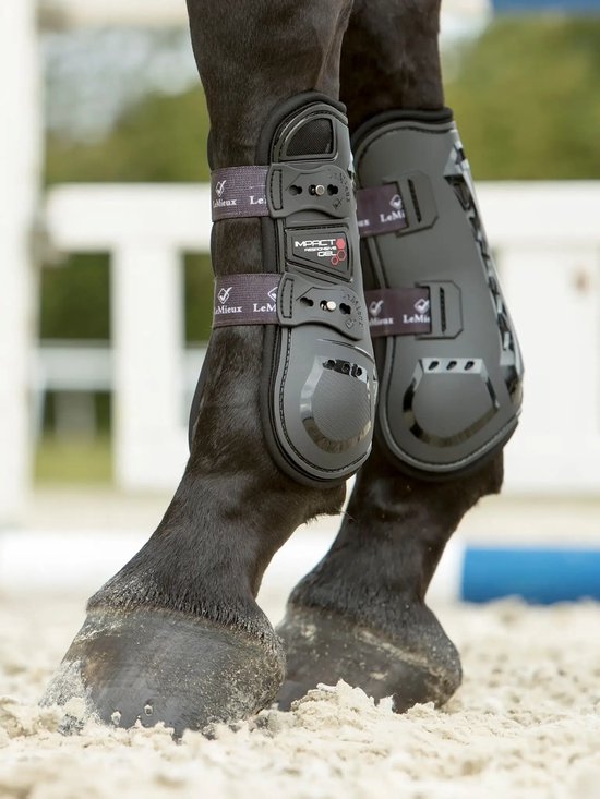 Zwarte paardenbenen met zwarte peesbeschermers met "IMPACT" print, gespen en LeMieux logo.