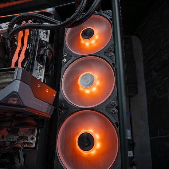Drie ventilatoren met oranje verlichting aan de zijkant van een gaming pc, met zicht op het moederbord.