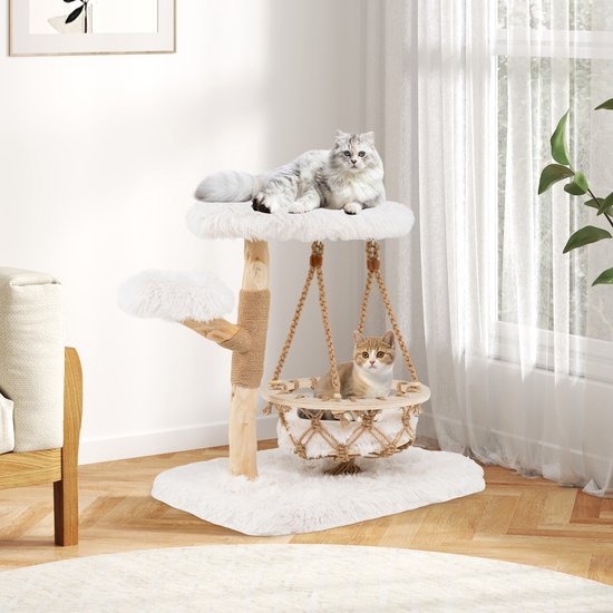 Kattenboom met witte pluche zittingen en een hangende mand, geplaatst in een woonkamer met meubels.