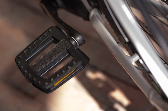 Pédale de vélo noire avec grip antidérapant et réflecteur orange, montée sur le cadre d'un vélo.