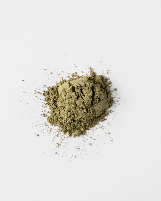 Kleine hoop gemalen biologische matcha poeder op een witte achtergrond.