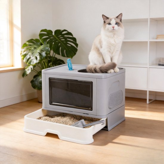 Grijze kattenbak met lade en een witte kat die bovenop zit. Een plant staat links.