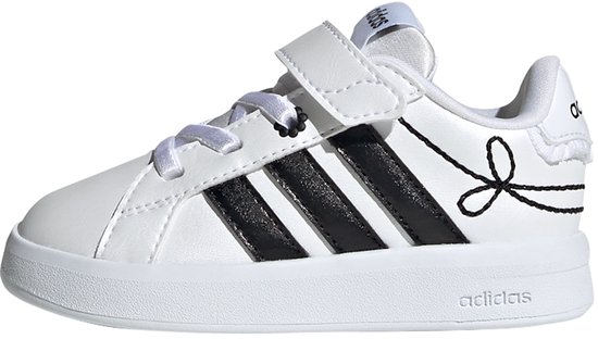 Witte sneaker met zwarte Adidas strepen, strikdetail, klittenbandsluiting en witte zool.