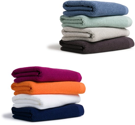Stapel van vier handdoeken in blauw, groen, grijs en bruin, naast een stapel van vier handdoeken in paars, oranje, wit en marineblauw.