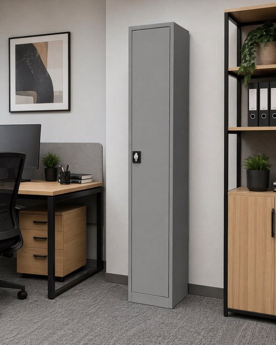 Grijze metalen archiefkast met één deur en een zwart handvat, naast een bureau en een open stellingkast.