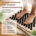 Voeten op een beige acupressuurmat met zwarte spikes, inclusief voetmat voor volledige ontspanning.