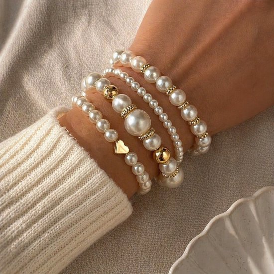 Set van vier armbanden met imitatieparels, gouden kraaltjes en een gouden hartje.
