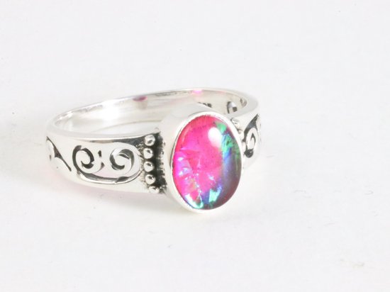 Zilveren ring met een ovale, felroze steen met groene en blauwe iriserende gloed. Band heeft opengewerkte krullen.