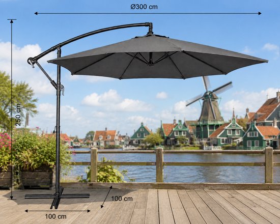 Grijze zweefparasol Ø300cm, 250cm hoog, 100x100cm voet. Molen op de achtergrond.