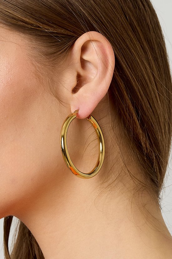 Gouden oorring aan het oor van een vrouw.