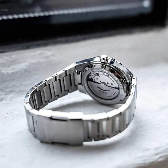 Zicht op de achterkant van een zilverkleurig Edifice horloge met automatisch uurwerk.