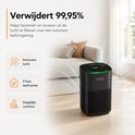 Zwarte luchtreiniger met groen verlicht display, in een woonkamer. Verwijder 99,95% van bacteriën en virussen voor schone lucht.
