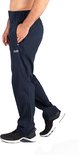 Man in donkerblauwe sportbroek met ritszak, gedragen met zwarte sportschoenen.