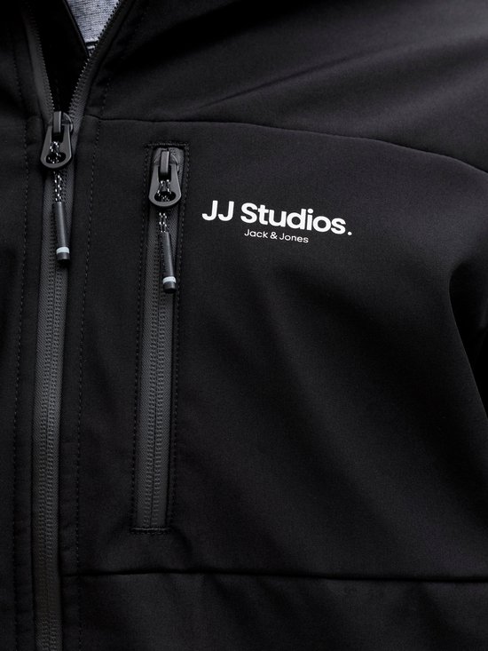 Detail van een zwarte jas met ritsen, 'JJ Studios. Jack & Jones' logo en een ritszakje.