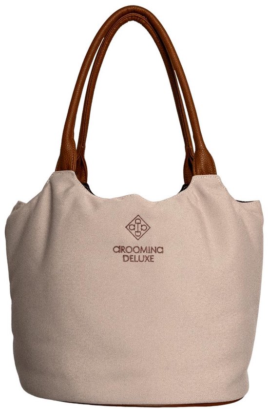 Beige canvas tas met bruine leren hengsels en bruine bodem. "GROOMING DELUXE" logo midden op de voorkant.