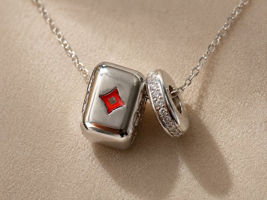 Zilveren ketting met een blokvormige hanger, versierd met een rood ruitvormig design, en een ronde hanger bezet met witte steentjes.