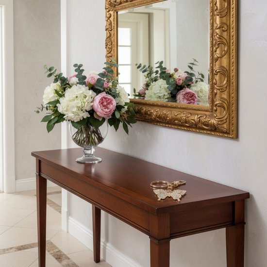 Gouden sleutelhanger met strass vlinderhanger op een houten console tafel, naast een bloemstuk.