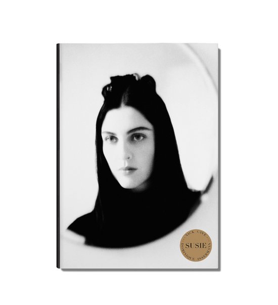 Zwart-wit portret van een vrouw met donker haar, een zwarte sjaal en een cirkelvormige spiegelreflectie.