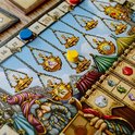 Detail van het spelbord met gouden lampen aan kettingen en een getekende tovenaar.