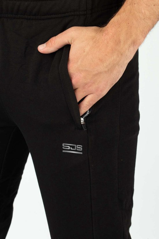 Zwarte joggingbroek met ritszak en logo, close-up van de hand in de zak.