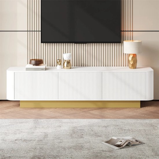 Witte dressoirkast met gouden voet en ribbeldeuren, met decoratie en lamp.