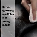 Een hand veegt met een witte doek over zwart leer, om restauratieresultaten te tonen.
