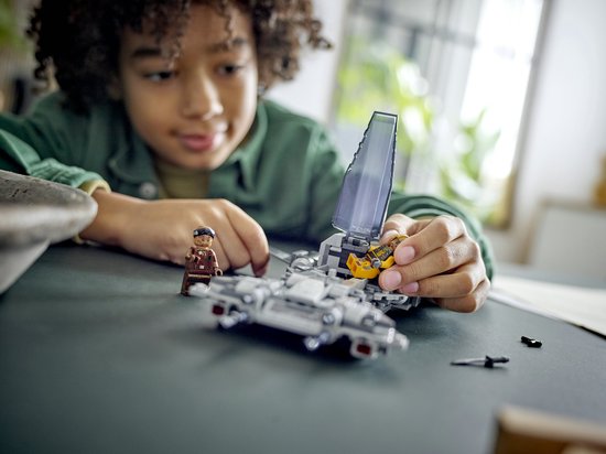 Close-up van een jongen die een grijze LEGO Star Wars snub fighter bouwt, met een minifiguur.