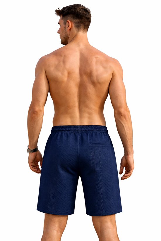 Man van achteren gezien, draagt donkerblauwe korte sportbroek.