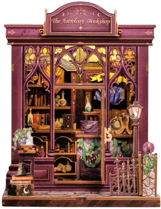 Paars miniatuurboekhuisje 'The Astrology Bookshop' met sierlijke deuren, lantaarnpaal en hekje. Interieur met boeken, potjes en decoraties.