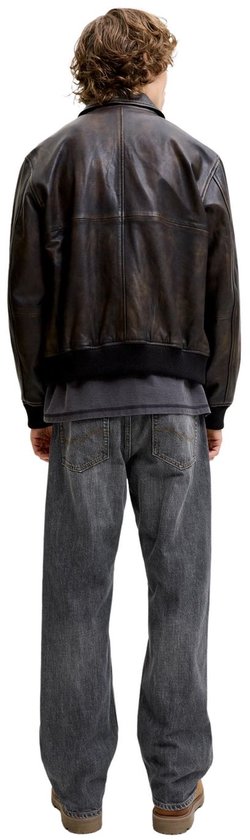 Achteraanzicht van model in grijze jeans en donkere jas.