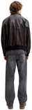 Achteraanzicht van model in grijze jeans en donkere jas.
