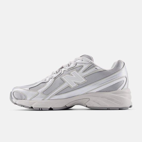 Een lichtgrijze New Balance 740 sneaker met metallic zilveren accenten, van de zijkant gezien.